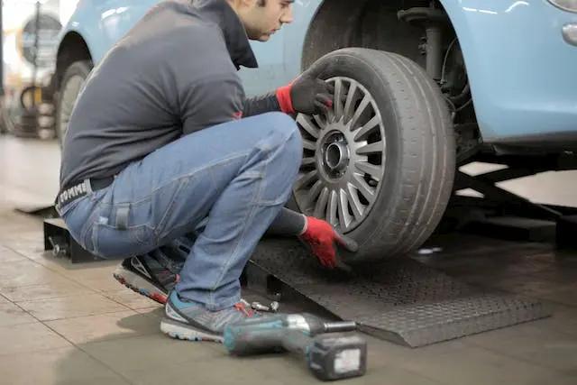 Técnico haciendo mantenimiento del coche a una rueda