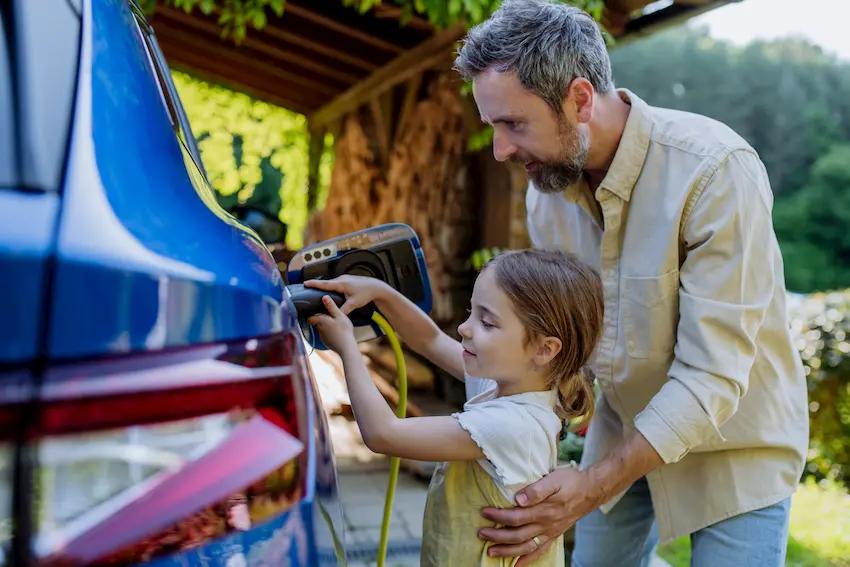 Hombre e hija cargan un coche eléctrico mejor que el de gasolina